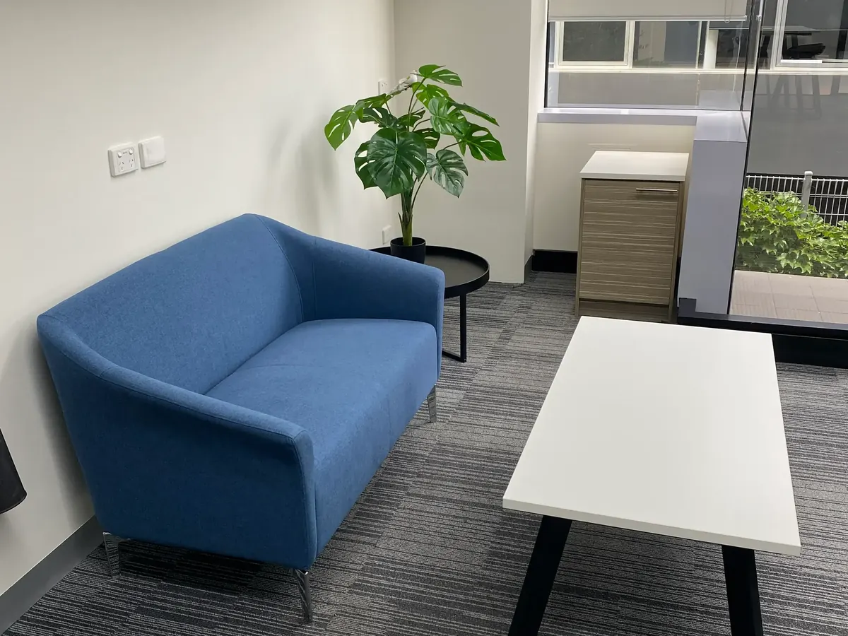 Clean office lounge area with a blue sofa